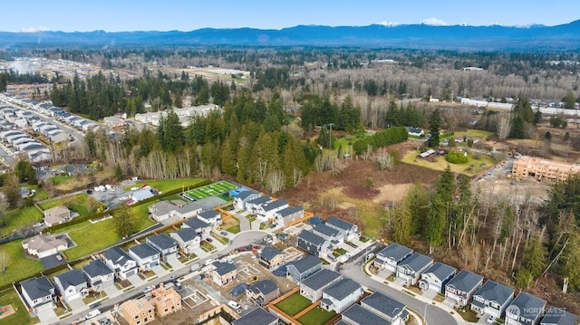 drone / aerial view featuring a wooded view, a mountain view, and a residential view