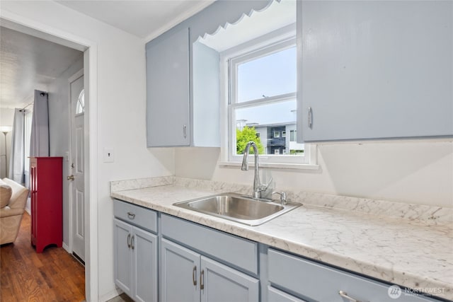 kitchen with gray cabinets, dark wood-style flooring, light countertops, and a sink