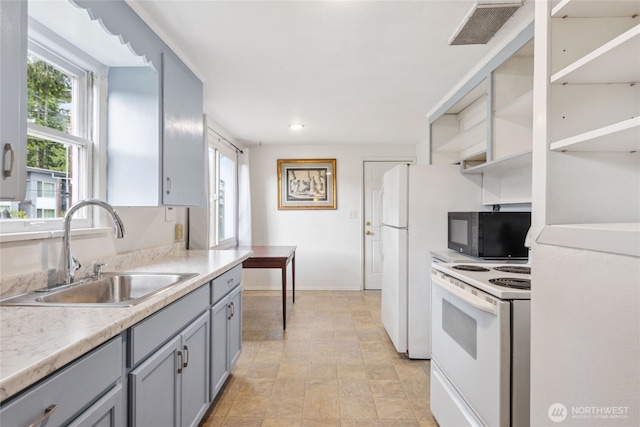 kitchen with black microwave, gray cabinetry, a sink, visible vents, and electric stove