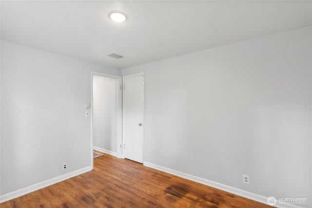 spare room featuring baseboards and wood finished floors