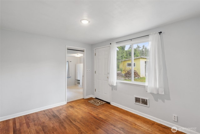 unfurnished room featuring visible vents, baseboards, and wood finished floors