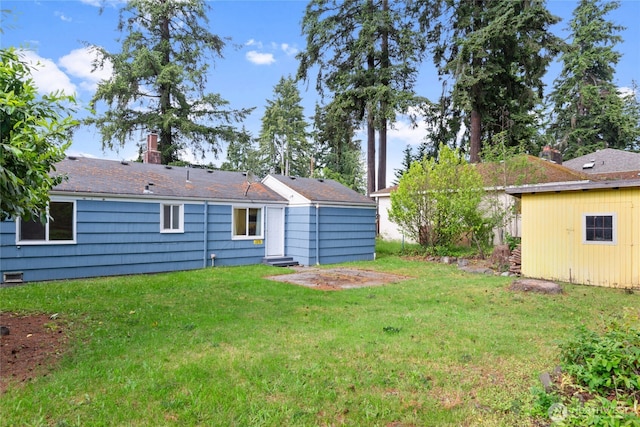 rear view of property with a chimney and a lawn