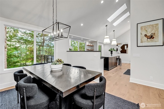 dining room with high vaulted ceiling, recessed lighting, a skylight, baseboards, and light wood-type flooring