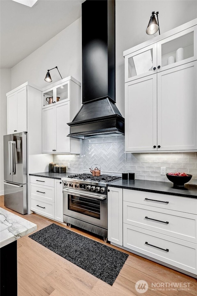 kitchen featuring wall chimney exhaust hood, appliances with stainless steel finishes, backsplash, and white cabinets