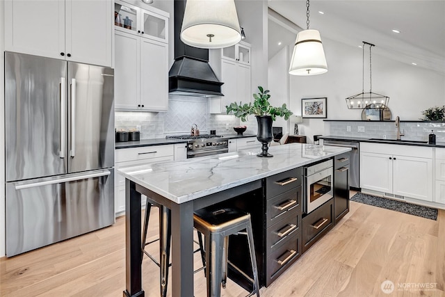 kitchen featuring light wood-type flooring, white cabinets, a sink, and high quality appliances