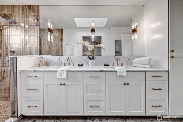 bathroom featuring double vanity, tiled shower, a skylight, and a sink