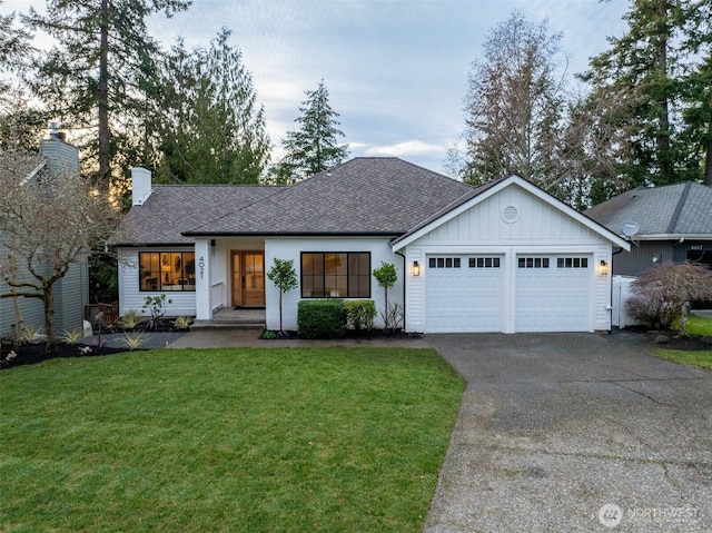 view of front facade featuring a chimney, board and batten siding, a garage, driveway, and a front lawn