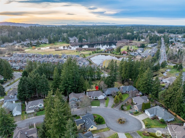 aerial view at dusk featuring a water view and a residential view