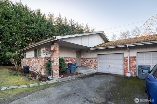 view of front of home featuring driveway, brick siding, and an attached garage