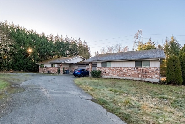 ranch-style house featuring aphalt driveway and brick siding