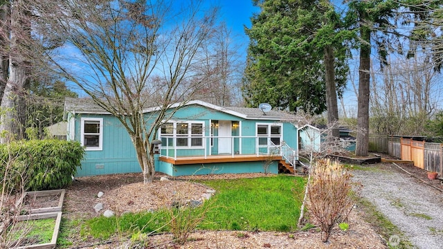 rear view of house featuring fence, driveway, a garden, covered porch, and crawl space