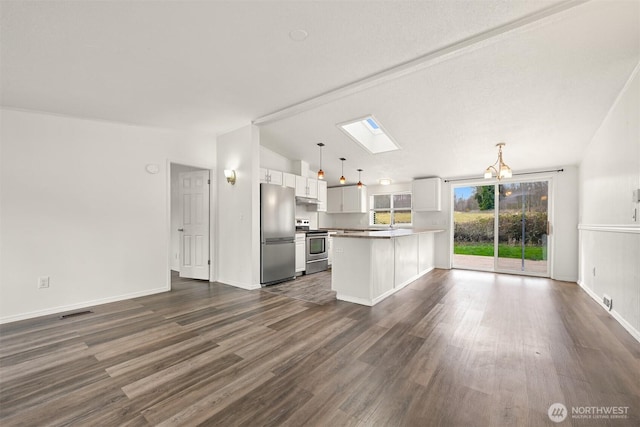 kitchen featuring lofted ceiling with skylight, dark wood-style floors, appliances with stainless steel finishes, a peninsula, and white cabinets