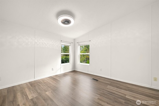 empty room featuring wood finished floors and visible vents