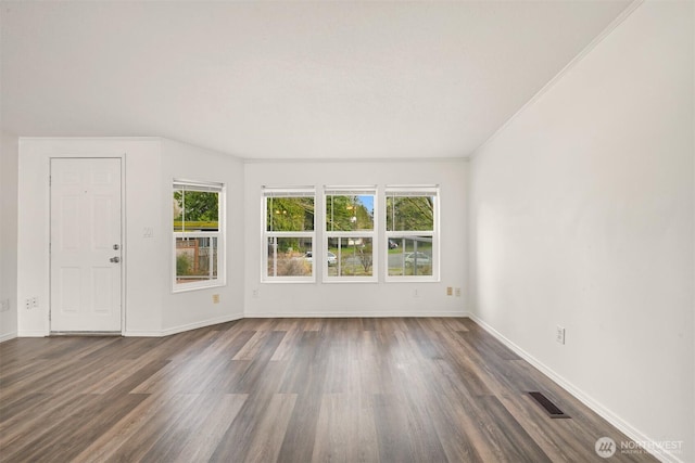 unfurnished room featuring visible vents, baseboards, dark wood finished floors, and crown molding