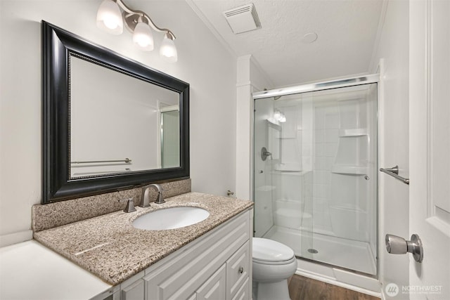 bathroom with visible vents, toilet, a stall shower, wood finished floors, and a textured ceiling