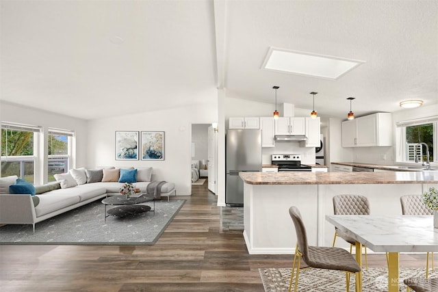 kitchen with lofted ceiling with skylight, a sink, under cabinet range hood, white cabinetry, and appliances with stainless steel finishes