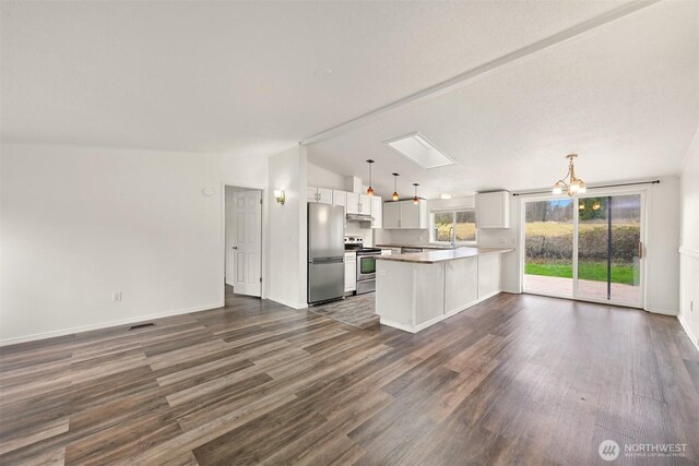 kitchen with a peninsula, vaulted ceiling with skylight, dark wood-type flooring, appliances with stainless steel finishes, and under cabinet range hood