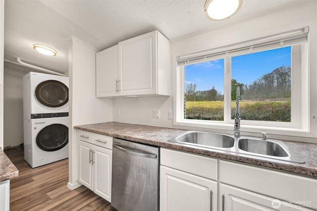 kitchen with stacked washer / dryer, white cabinets, dishwasher, and a sink