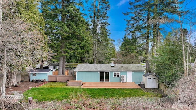 back of house with fence, a yard, a deck, an outbuilding, and a storage unit