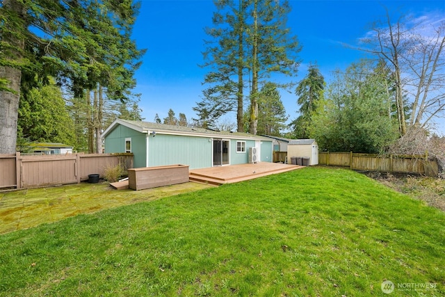 rear view of property featuring a fenced backyard, a shed, a yard, an outdoor structure, and a wooden deck