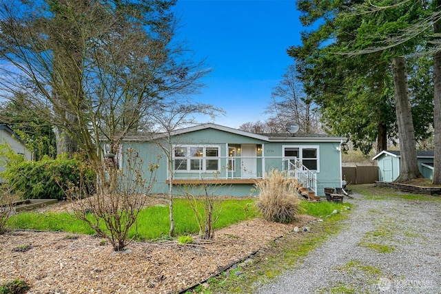 view of front of home featuring driveway, a storage shed, an outdoor structure, and fence