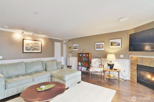 living room with wainscoting, crown molding, wood finished floors, and a tile fireplace