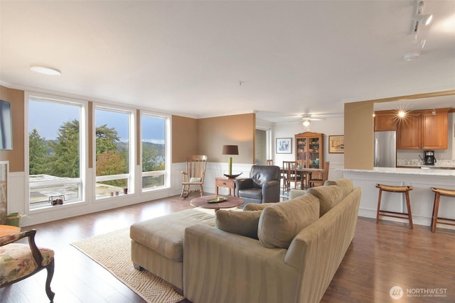 living room with dark wood-style flooring, a wainscoted wall, and crown molding