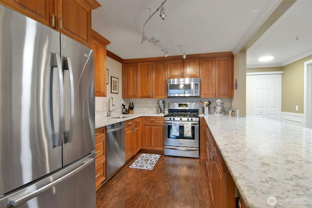 kitchen with appliances with stainless steel finishes, brown cabinetry, dark wood-type flooring, ornamental molding, and a sink