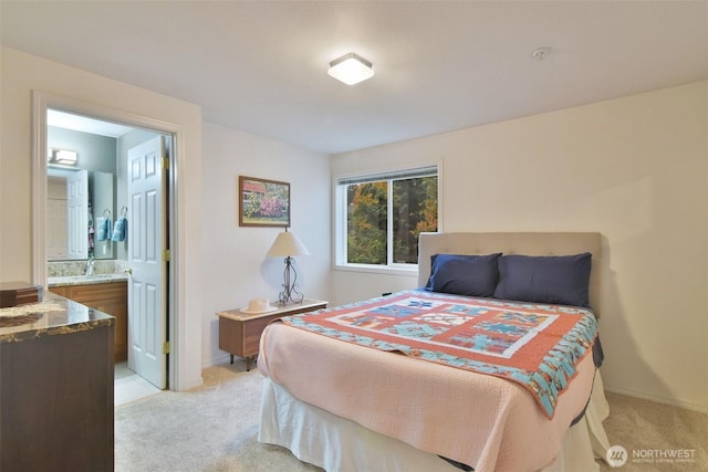 bedroom featuring baseboards, connected bathroom, and light colored carpet