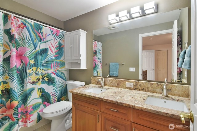 bathroom with toilet, double vanity, and a sink