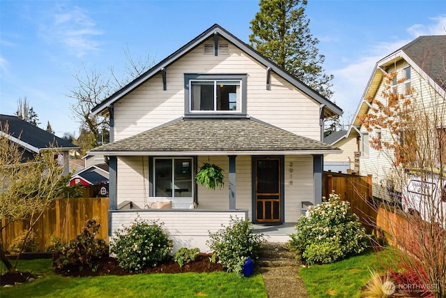 bungalow-style home featuring a porch, fence, and roof with shingles