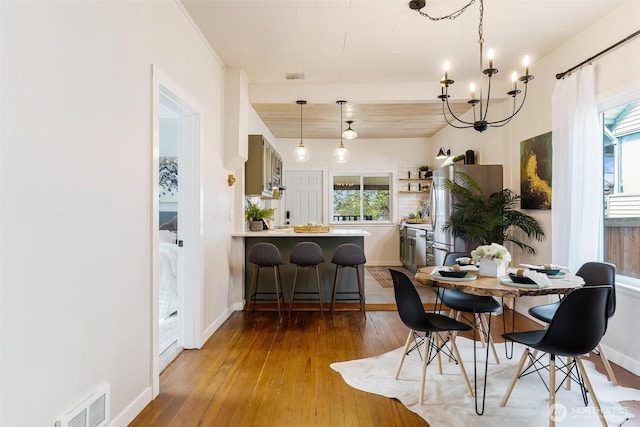 dining room featuring visible vents, plenty of natural light, a notable chandelier, and hardwood / wood-style floors