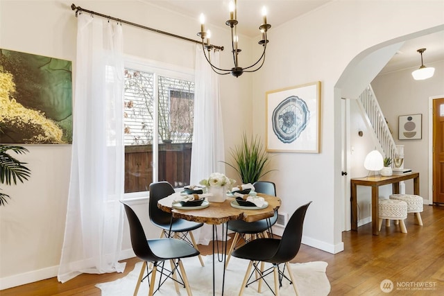 dining room featuring arched walkways, wood finished floors, and ornamental molding