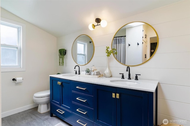 full bathroom featuring double vanity, toilet, lofted ceiling, and a sink