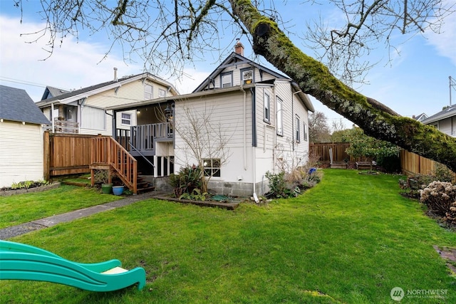 rear view of house featuring fence, stairway, a chimney, a deck, and a yard