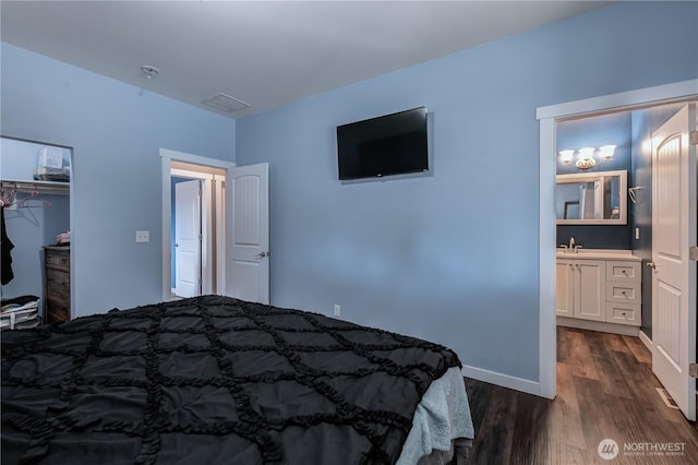 bedroom with dark wood-style floors, a closet, visible vents, a sink, and baseboards