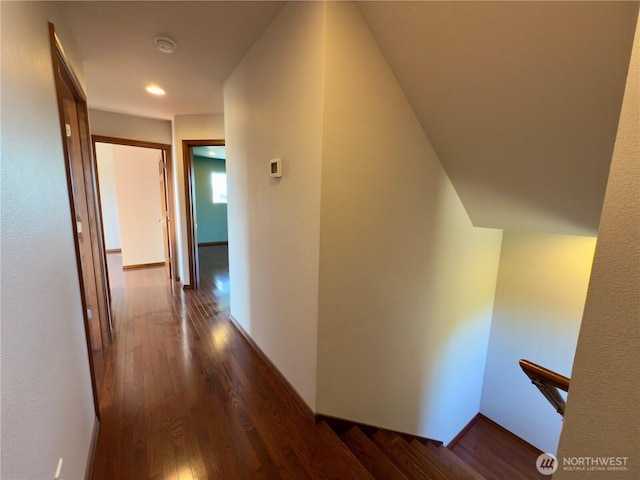 corridor with baseboards, dark wood finished floors, and an upstairs landing