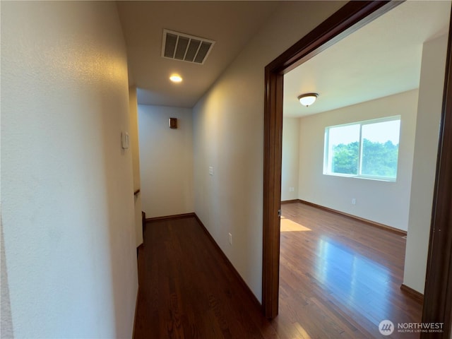 hallway featuring visible vents, baseboards, and wood finished floors