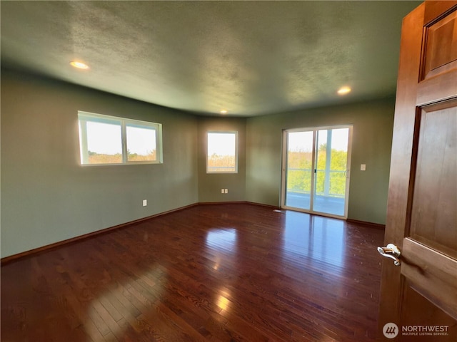 spare room with a textured ceiling, recessed lighting, dark wood finished floors, and baseboards