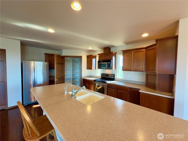 kitchen with brown cabinetry, light countertops, stainless steel appliances, a sink, and recessed lighting