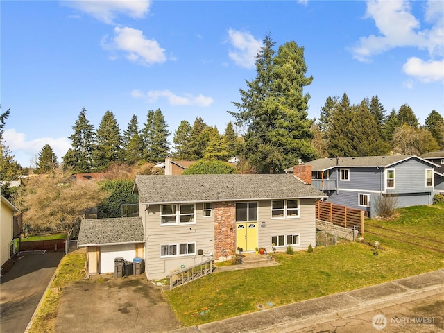 raised ranch with roof with shingles, central AC unit, entry steps, fence, and a front lawn