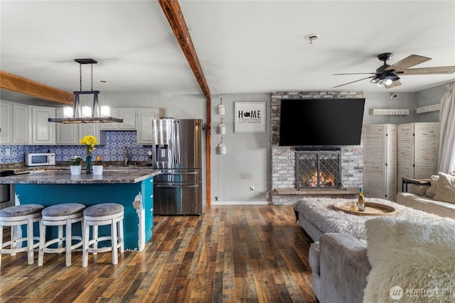 kitchen featuring beam ceiling, stainless steel refrigerator with ice dispenser, tasteful backsplash, white microwave, and open floor plan