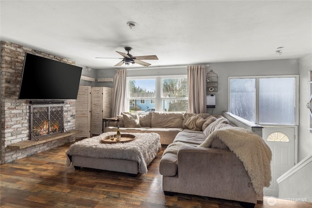 living area featuring a fireplace, a ceiling fan, and wood finished floors