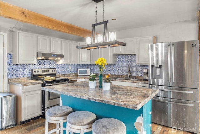 kitchen with appliances with stainless steel finishes, backsplash, a sink, and under cabinet range hood