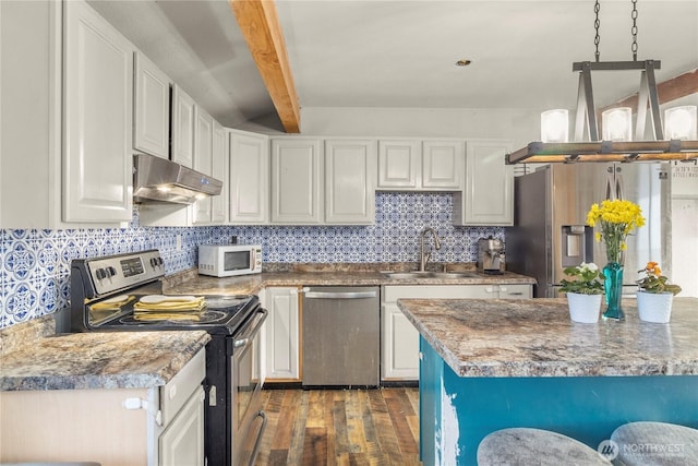 kitchen featuring under cabinet range hood, a sink, appliances with stainless steel finishes, beam ceiling, and decorative backsplash