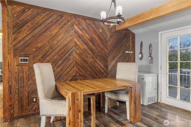 dining space with wood-type flooring, visible vents, beamed ceiling, and an inviting chandelier