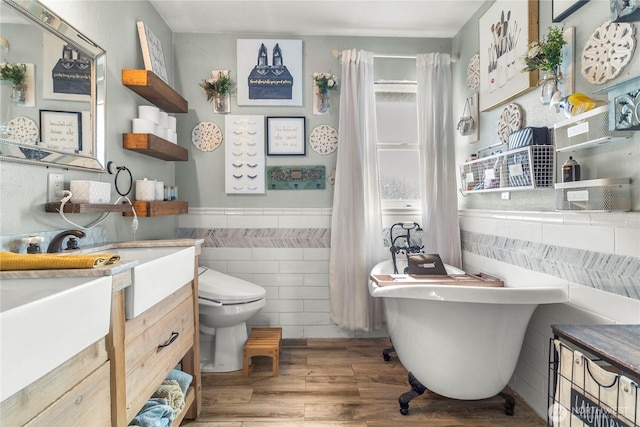 bathroom with a freestanding bath, wood finished floors, tile walls, and vanity