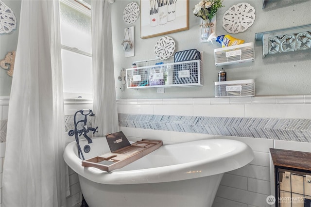 full bathroom featuring a soaking tub, tile walls, and a wainscoted wall