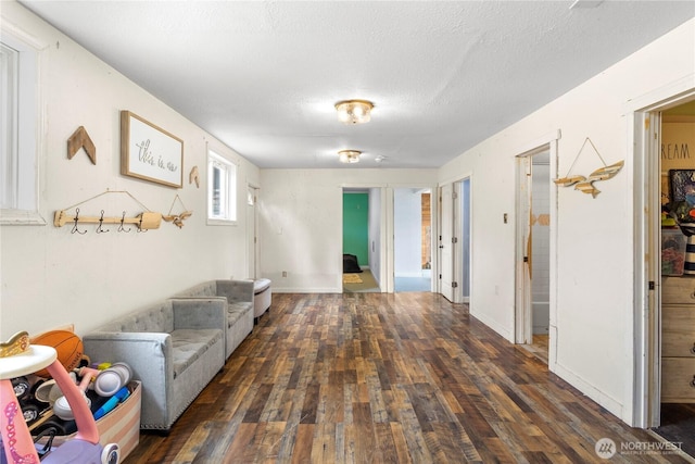 living area with a textured ceiling, baseboards, and wood finished floors