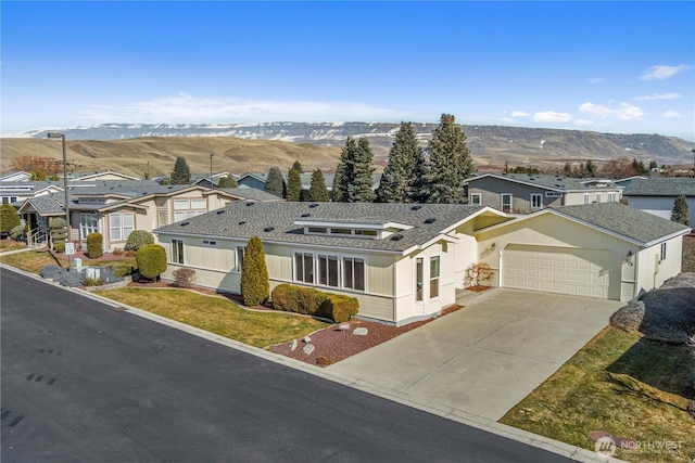 view of front of property featuring a garage, driveway, a residential view, and a mountain view